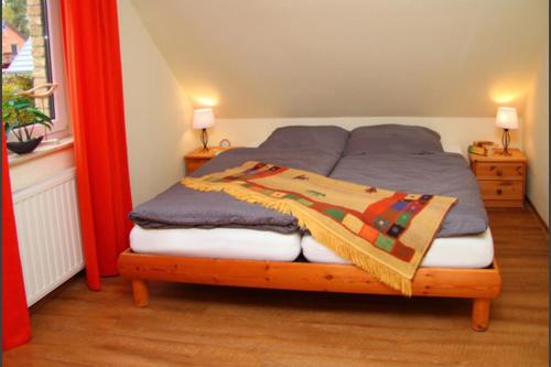 um quarto com uma cama com um cobertor em 2 - Schönes Ferienhaus für die ganze Familie direkt an der Müritz em Marienfelde