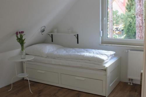 a white bedroom with a bed and a window at K 104 OG - stilvolle Ferienwohnung am See mit Balkon & Sauna in Röbel an der Müritz in Marienfelde