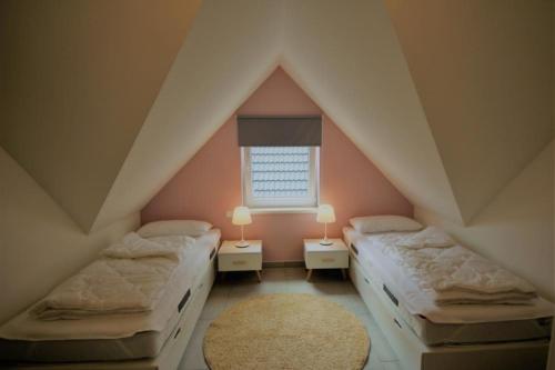 a attic bedroom with two beds and a window at K 100 OG - charmante Ferienwohnung für die ganze Familie in Röbel an der Müritz in Röbel
