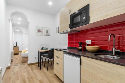 a kitchen with a sink and a red wall at Charming Chueca Center in Madrid