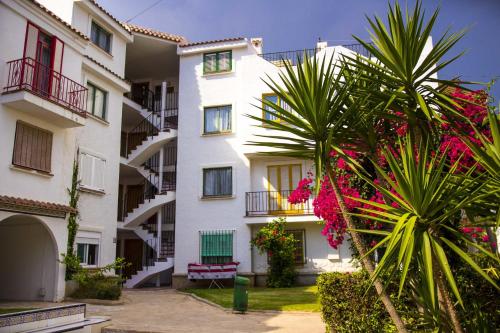 a white building with a palm tree in front of it at Apartments Kione Playa Romana Park in Alcossebre