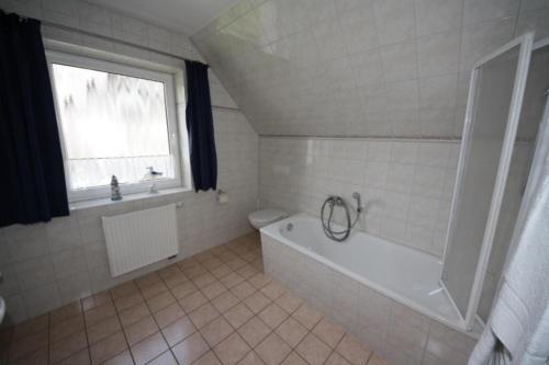 een witte badkamer met een bad en een raam bij 26 - Schoenes Ferienhaus mit Kamin fьr die ganze Familie direkt am See in Roebel in Röbel