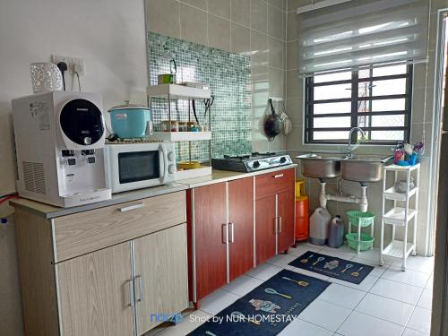 una cocina con 2 microondas en la encimera en Nur’s Homestay, en Kuala Kelawang