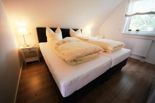 a bedroom with a bed with white sheets and a window at K 102 OG - stilvolle Ferienwohnung an der Müritz in Röbel an der Müritz in Marienfelde