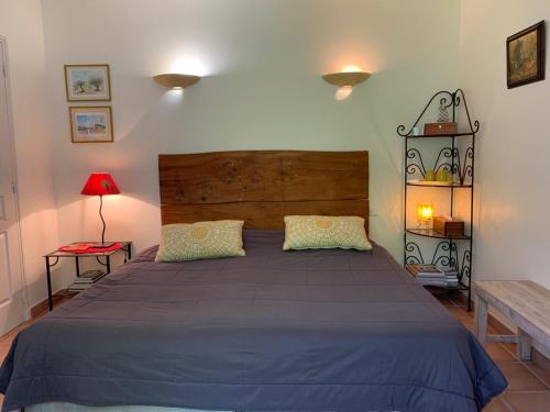 a bedroom with a large bed with a wooden headboard at Chambres d'hôtes "LA NESQUE" in Venasque