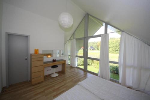 a bedroom with a desk and a large window at W9 - Traumhaftes Ferienhaus mit Kamin & grossem Garten in Roebel in Marienfelde