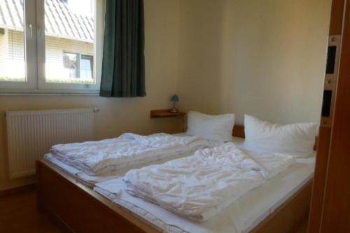 1 cama blanca grande en una habitación con ventana en 30 EG - Gemuetliche Ferienwohnung direkt am See in Roebel Mueritz, en Marienfelde