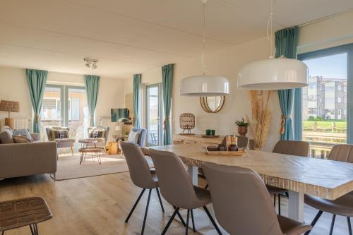 un soggiorno con un grande tavolo in legno e sedie di Dormio Villapark Duynzicht a Julianadorp