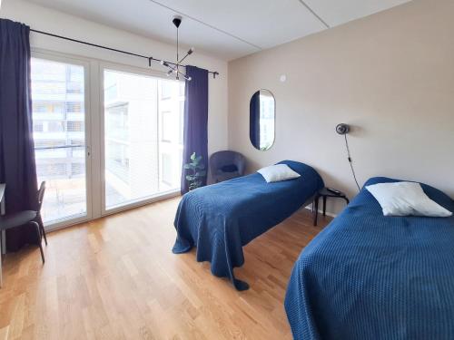 a bedroom with two beds and a large window at Studio next to train station, 7 mins by train to airport in Vantaa