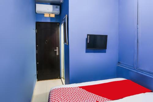a blue room with a bed with a red blanket at OYO 93772 Iconiq Rooms in Bekasi