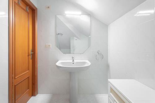 ein weißes Badezimmer mit einem Waschbecken und einem Spiegel in der Unterkunft Chalet Itsaso in Canet d'en Berenguer