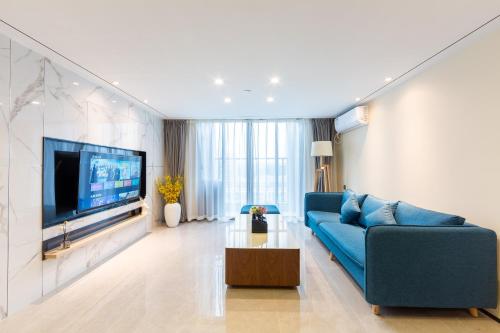 a living room with a blue couch and a tv at Serveyou International Apartment - Free Airport Pickup Service & Free Pazhou Complex Shuttle Bus & Free Sanyuan Li Xiaobei Baiyun Wholesale Market shuttle bus in Guangzhou