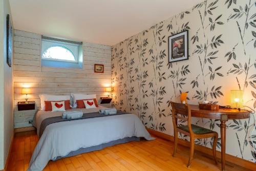a bedroom with a bed and a table and a desk at Le Relais - Maison avec grand jardin in Bannalec