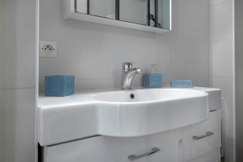 a white bathroom sink with two blue candles on it at Charmant appartement lumineux pour 4 personnes au Pouliguen in Le Pouliguen