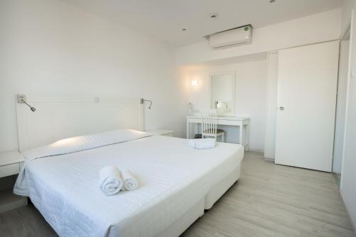 a white bedroom with two towels on a bed at Liquid Hotel Apartments in Ayia Napa