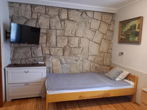a bedroom with a stone wall with a bed and a tv at Villa Laura in Polanica-Zdrój