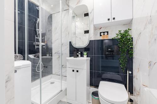 a white bathroom with a toilet and a shower at SuperApart Saska 48a in Warsaw