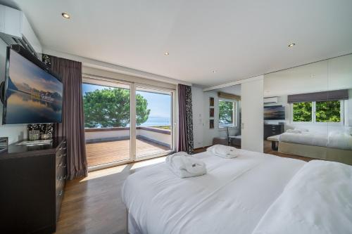 una camera da letto con un grande letto bianco e una grande finestra di Lausanne area Luxurious 4-Bedroom Villa on the Lake by GuestLee a Pully