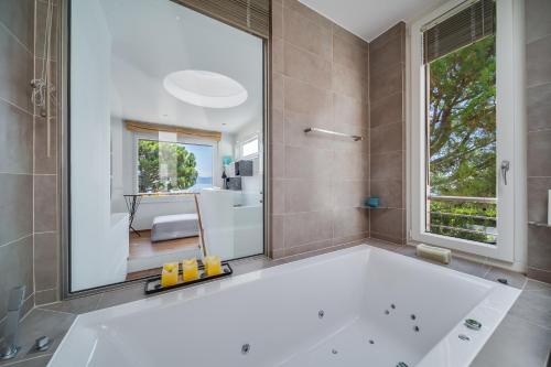 een badkamer met een bad en een groot raam bij Lausanne area Luxurious 4-Bedroom Villa on the Lake by GuestLee in Pully