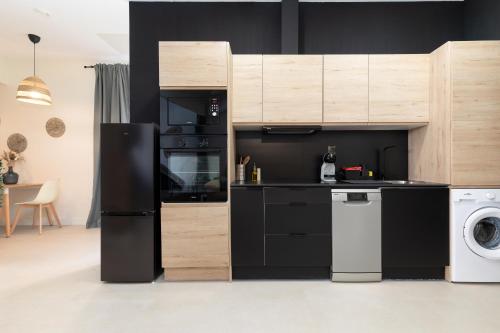 eine Küche mit einem schwarzen Kühlschrank, einer Waschmaschine und einem Trockner in der Unterkunft RINCONCITO DEL TURIA ZAPA2 in Valencia
