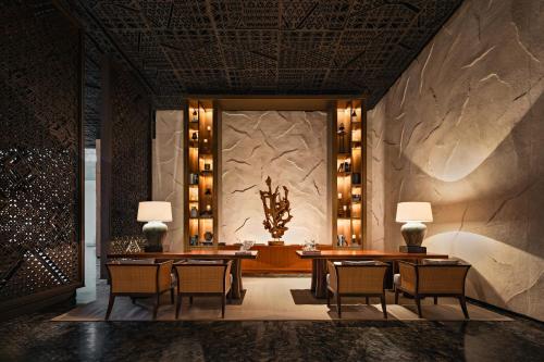 ein Esszimmer mit Tischen und Stühlen und einer Steinmauer in der Unterkunft Bali Beach Hotel in Sanur