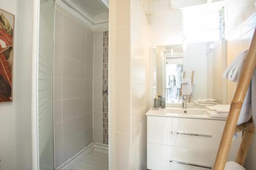 La salle de bains blanche est pourvue d'une douche et d'un lavabo. dans l'établissement 15 - LE VACOA - CHAMBRE 15 ETG D, à Saint-Paul