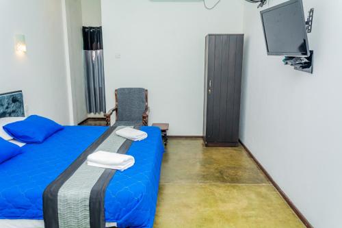 a bedroom with a blue bed and a flat screen tv at ShiCo Transit Hotel in Negombo