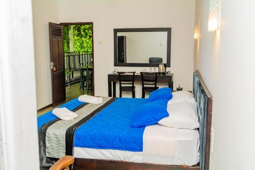 a bedroom with a bed with blue sheets and a table at ShiCo Transit Hotel in Negombo