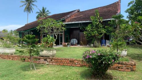 a house with trees and plants in the yard at Aaira 8Pari Riverview Lodge in Kota Bharu
