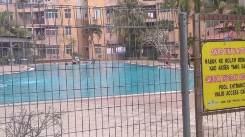 a fence in front of a swimming pool with a sign at Budget Homestay Mantin Villa with 3 rooms and big swimming pool in Mantin