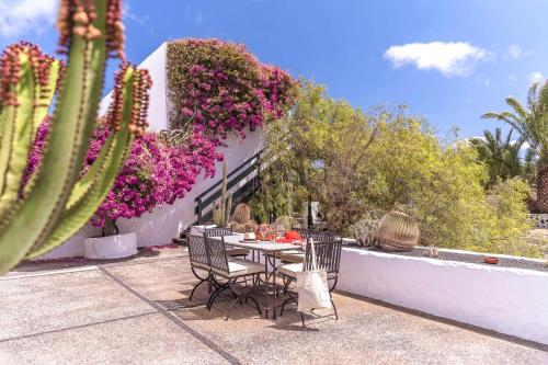 a table and chairs in a garden with flowers at Hotel Bodega EL GRIFO in San Bartolomé
