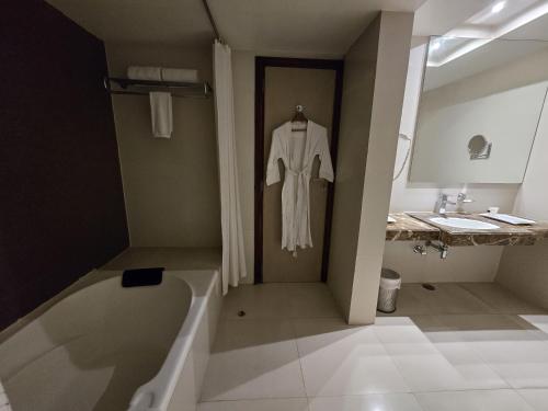 a bathroom with a robe hanging next to a bath tub at Hotel Daaysco Oley Allo in Guwahati