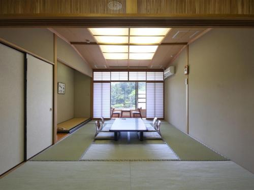 an empty room with a table and a window at Unohama Onsen Royal Hotel Kobayashi in Joetsu