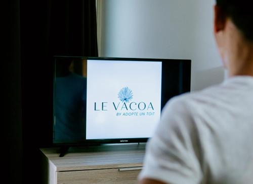a woman sitting in front of a television at 7 - LE VACOA - CHAMBRE 7 ETG g in Saint-Paul