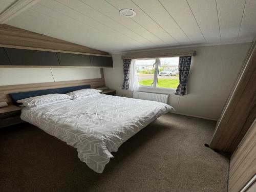a bedroom with a bed and a window at Lovely 2-Bed Caravan in Prestonpans in Longniddry