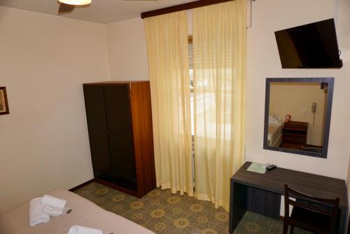 a room with a bed and a dresser and a mirror at Hotel Diana in Riva del Garda