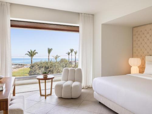 a bedroom with a large bed and a large window at Amirandes, A Grecotel Resort to Live in Gouves