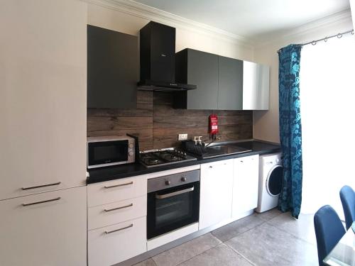 a kitchen with white cabinets and a stove top oven at Central 2BR Apartment with Balcony by Apricus Design in Msida