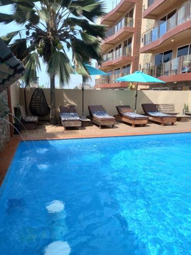 a large blue swimming pool with lounge chairs and a building at LA SUNSET in Accra