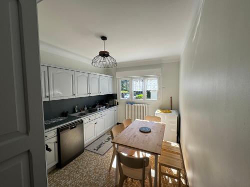 une cuisine avec des armoires blanches et une table et des chaises dans l'établissement Maison St Lary 4Ch 10pers jardin, à Saint-Lary-Soulan