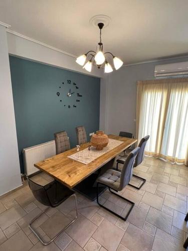 einen Esstisch mit Stühlen und eine Uhr an der Wand in der Unterkunft Comfortable apartment in Kiato in Kiato