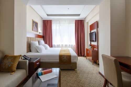 une chambre d'hôtel avec un lit et un canapé dans l'établissement Regardal Hotel, à Almaty
