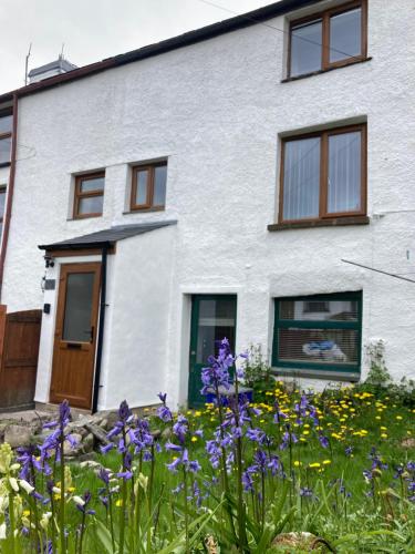 a white house with flowers in front of it at Leven's Rest in Backbarrow