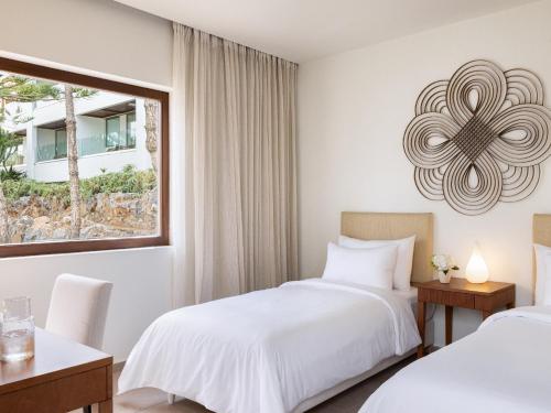 a bedroom with two beds and a window at Amirandes, A Grecotel Resort to Live in Gouves