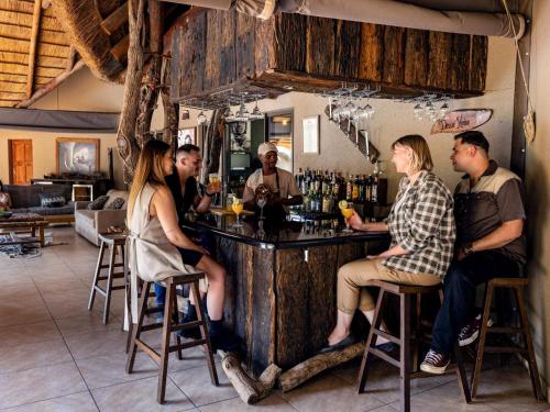 een groep mensen die aan een bar zitten bij Sable Ranch Bush Lodge in Brits