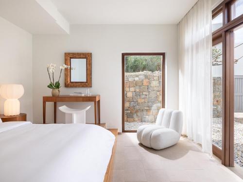 a bedroom with a bed and a chair and a window at Amirandes, A Grecotel Resort to Live in Gouves