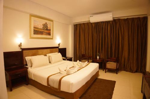 a hotel room with a large bed with white sheets at Fu Wang Dominous Resort in Cox's Bazar