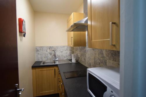 a small kitchen with a sink and a microwave at Woodlands Lodge Ilford in Ilford