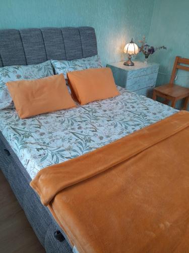 a bed with two orange pillows on top of it at Cozy Apartment in Alūksne