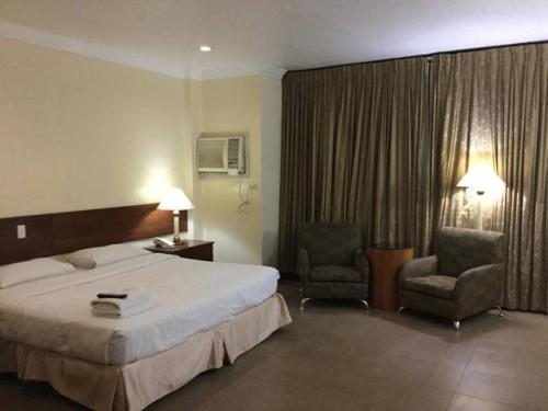 um quarto de hotel com uma cama e duas cadeiras em Dottie's Place Hotel & Restaurant em Butuan